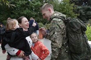 Un recluta ruso habla con su esposa e hijos fuera de un centro de reclutamiento militar en Volzhskiy, región de Volgogrado, Rusia, el miércoles 28 de septiembre de 2022.
