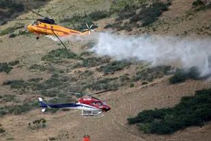 Dos helicópteros combaten un incendio en Springville, Utah, el lunes 1 de agosto de 2022. (Kristin Murphy/The Deseret News vía AP)