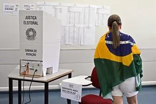 ARCHIVO-. Una mujer envuelta en una bandera brasileña vota en un colegio electoral durante las elecciones legislativas y presidenciales, en Brasilia, Brasil, el 2 de octubre de 2022. - (Foto por EVARISTO SA / AFP)
