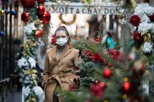 Una mujer con un tapabocas debido a la pandemia de coronavirus, pasa frente a escaparates con temas navideños dentro de Burlington Arcade en el centro de Londres, el 23 de noviembre de 2020