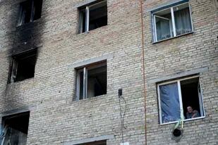 Una mujer mira por la ventana en un edificio destruido por ataques en Gorenka, a las afueras de Kiev, Ucrania, el 8 de junio de 2022. (AP foto/Natacha Pisarenko)