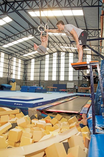 El gimnasio es (casi) su casa. Siguiendo las instrucciones de papá, Valentino prueba las anillas, mientras Ciro se prepara para subir.
