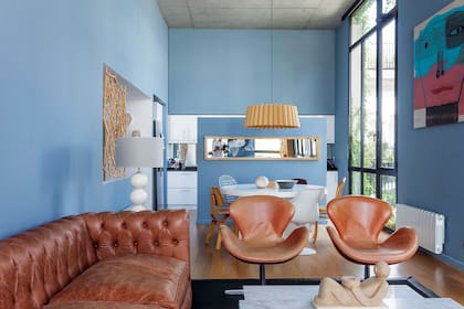 En el living, sillones giratorios de cuero claro ‘Swan’ (Newton). En la pared de la izquierda, una obra de arte santiagueño en madera de algarrobo tamiza con distinción la vista al recibidor.