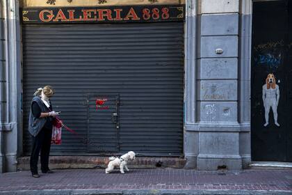 Una mujer pasea a su perro en el barrio de San Telmo en plena cuarentena social y obligatoria en el país. Por @piovanopablo