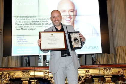Feliz, el director muestra la placa que lo declara Personalidad Destacada de la Cultura