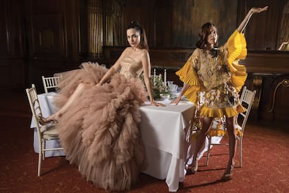 Vestidas por el diseñador argentino Javier Saiach, Carla Moure y Laurita Laprida posan sobre la mesa
