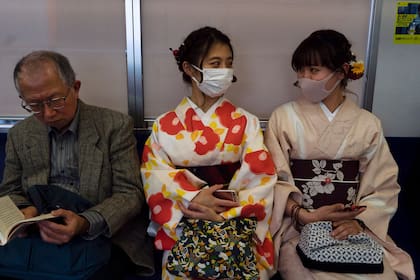 Dos mujeres conversan -barbijo mediante- en un tren de Kioto