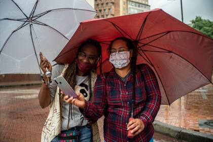 Las mejores imágenes de un colectivo que narra la vida actual en los distintos países. En Bogotá, dos mujeres protegidas, contra la lluvia y contra el virus; por Federico Ríos Escobar