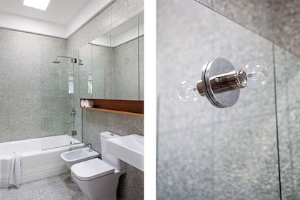 En el baño principal se incorporaron dos claraboyas para tener luz natural. El revestimiento es de mosaico granítico con fondo cemento natural y piedra blanca. El mueble espejado tiene base de lenga y artefactos Roca.