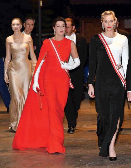 A la noche, Carolina y Charlene protagonizaron un auténtico duelo de estilo. Mientras la hija de Grace Kelly impactó con un vestido con capa asimétrica y sin manga de Stella McCartney, Charlene optó por un traje de noche bicolor con tajo lateral que realzaba su figura.