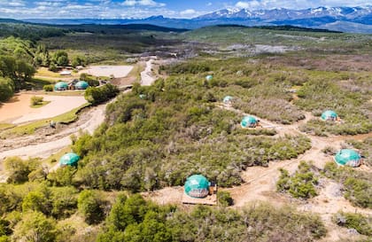 Vista aérea de los Domos rodeados de verde y con las montañas de fondo.
