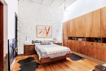 En la cama, edredón de plumas sintético, manta símil mohair con flecos como pie (todo de Arredo) y almohadones (Pezkoi). Sobre la mesa de luz, cuadro ‘Pantone’ (Petite Margot).