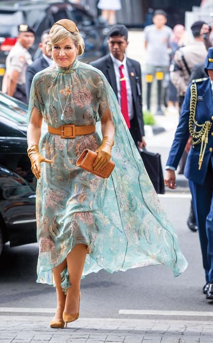 En Yakarta, Su Majestad impactó con un vestido midi con capa y estampa floral de Natan. Lo accesorizó con casquete a juego y joyas con historia: collar, pulsera y pendientes de aguamarina de la reina Juliana, pulsera familiar de diamantes, y su pulsera de boda. Culminó su look con reloj Patek Philip