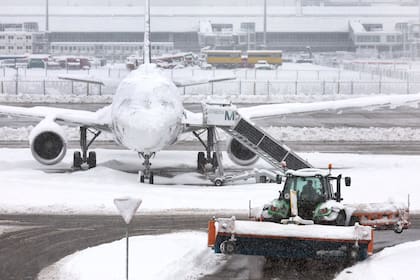 02 December 2023, Bavaria, Munich: A snow plow drives in front of a plane in the snowstorm at the airport. Photo: Karl-Josef Hildenbrand/dpa