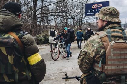 05-03-2022 Un joven camina, junto a su bici, mientras dos soldados ucranianos le observan, a 5 de marzo de 2022, en Irpin (Ucrania). El ejército de Ucrania resiste por el momento el duro asedio de Rusia a su capital, Kiev, donde se recrudecen los combates. Naciones Unidas calcula que este domingo, 6 de marzo, el número de refugiados ucranios podría ascender a 1,5 millones. El número de civiles muertos en el conflicto se acerca a los 3.000 y casi 4.000 heridos según fuentes del gobierno ucraniano.  Después de que Visa y Mastercard se unieran  a la lista de empresas que están cerrando sus filiales en Rusia, Putin dijo que las sanciones impuestas por Occidente y sus compañías  son «una declaración de guerra». Además el presidente ruso  firmó un decreto por el que ordena al Consejo de Ministros elaborar un listado de países que han realizado «acciones no amistosas». POLITICA Diego Herrera - Europa Press