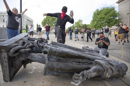 10 de junio de 2020, EE. UU., Saint Paul: un hombre patea la estatua de Cristóbal Colón que se encuentra en el suelo después de ser derribado por activistas nativos americanos en el Estado de Minnesota