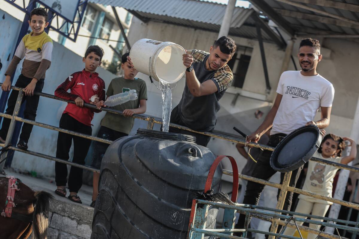 18 October 2023, Palestinian Territories, Khan Yunis: Palestinians fill containers with drinking water from a water distribution vehicle, amid the water crisis caused by the Israeli siege on the Gaza Strip. Photo: Mohammed Talatene/dpa (Photo by Mohammed Talatene/picture alliance via Getty Images)