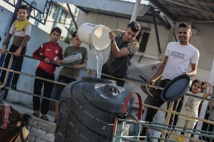 18 October 2023, Palestinian Territories, Khan Yunis: Palestinians fill containers with drinking water from a water distribution vehicle, amid the water crisis caused by the Israeli siege on the Gaza Strip. Photo: Mohammed Talatene/dpa (Photo by Mohammed Talatene/picture alliance via Getty Images)