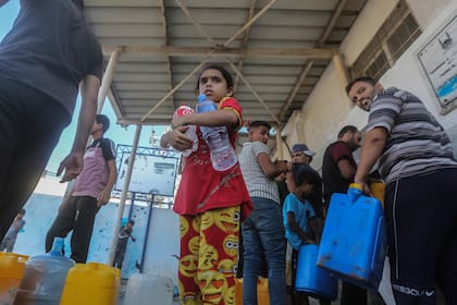 Los palestinos llenan contenedores con agua potable desde un vehículo de distribución de agua, en medio de la crisis hídrica provocada por el asedio israelí a la Franja de Gaza