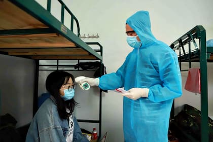 (200317) -- HANOI, 17 marzo, 2020 (Xinhua) -- Imagen del 16 de marzo de 2020 de un doctor verificando la temperatura de una mujer en una instalación de cuarentena, en la provincia de Vinh Phuc, en el norte de Vietnam. El Ministerio de Salud de Vietnam dijo el martes por la tarde que cinco personas locales más dieron positivo para el nuevo coronavirus, trayendo el total de casos confirmados de COVID-19 en el país a 66. (Xinhua/VNA) (eb) (rtg)