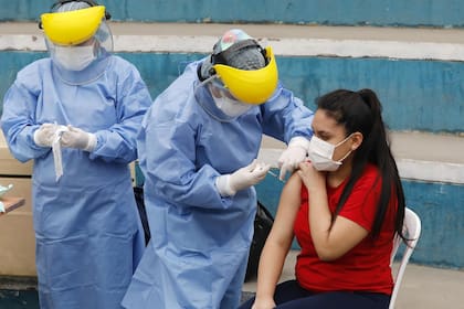 (200821) -- LIMA, 21 agosto, 2020 (Xinhua) -- Un trabajador médico aplica una vacuna a una mujer para prevenir la influenza como parte de una campaña de salud durante el estado de emergencia sanitaria en la municipalidad de Villa María del Triunfo, en Lima, Perú, el 21 de agosto de 2020. Cines, teatros, gimnasios y hasta casinos empiezan a tomar su ritmo en una "nueva normalidad" por la enfermedad causada por el nuevo coronavirus (COVID-19) en América Latina, mientras algunos países participan en la fase 3 para probar una vacuna que ayude a combatir el virus. (Xinhua/Mariana Bazo) (mb) (mm) (vf) (dp) 

