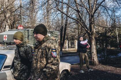 23/02/2022 Unos soldados del ejército ucraniano caminan frente a un padre y su bebe, a 23 de febrero de 2022, en Chasiv Yar, Oblast de Donetsk (Ucrania). POLITICA Diego Herrera - Europa Press