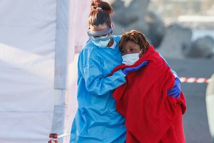 25-08-2021 Una sanitaria ayuda a una mujer migrante a desembarcar de la guardamar Talía a 25 de agosto de 2021, en Arguineguín (Gran Canaria), Islas Canarias. SOCIEDAD MAURICIO DEL POZO