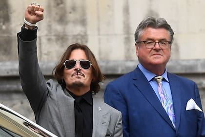 Johnny Depp, con la mano en alto, al dejar el tribunal inglés, en donde se llevó adelante el juicio contra The Sun