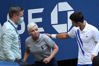 6 de septiembre de 2020; Flushing Meadows, Nueva York, Estados Unidos; Novak Djokovic de Serbia y un oficial del torneo atienden a un juez de línea que fue golpeado con una pelota por Djokovic contra Pablo Carreño Busta de España.