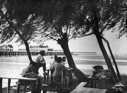 8 de diciembre de 1957: una familia almuerza en el espigón del balneario, rodeada de sauces y tibias aguas.