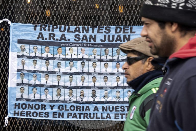 A flag with the portraits of the 44 members of the Argentine Navy who died during the sinking of ARA San Juan submarine on November 15, 2017, hangs from the entrance of a court in Rio Gallegos, Santa Cruz on March 3, 2026, where the trial of four former high-ranking Navy officers is being held. Argentina opens a trial on March 3 into a submarine implosion that killed 44 sailors in November 2017, the country's worst naval disaster in decades, and whose circumstances remain unclear. (Photo by WALTER DIAZ / AFP)