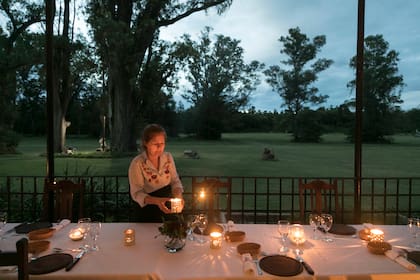 A la luz de las velas, la mesa servida en la galería con vista al extenso parque.