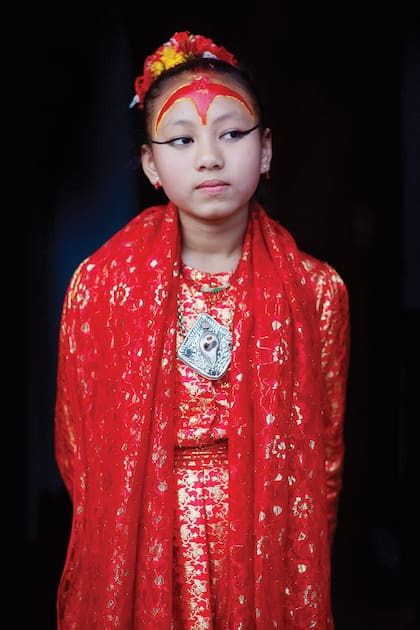 A los 12 años en Patan, Nepal, vestida de rojo –el color de la buena suerte y la energía– sola, descalza y con los ojos delineados de negro, espera a los devotos que van a arrodillarse a sus pies para obtener su bendición.