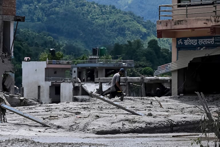 A man salvages belongings from his house lying deluged in sludge after flash floods in the Devighat area in Nepal's Nuwakot district on August 27, 2026. Rescue teams rushed on August 27 to find more than 1,300 people missing on the Nepal-Tibet border in flash floods and landslides that killed at least 165 and swept away entire villages. (Photo by Prakash MATHEMA / AFP)
