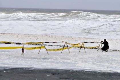 Un hombre toma fotografías de la espuma y el rocío del mar que cubre el paseo marítimo durante el paso de un ciclón subtropical en Punta del Este, Uruguay