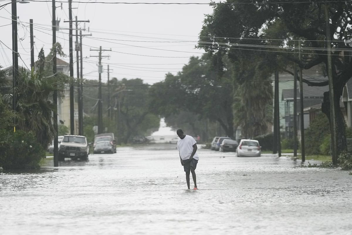 A man walks down the middle of a flooded road as Galveston, Texas, as Tropical Storm Beryl wanes on Monday, July 8, 2024. (Elizabeth Conley/Houston Chronicle via AP)