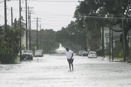 A man walks down the middle of a flooded road as Galveston, Texas, as Tropical Storm Beryl wanes on Monday, July 8, 2024. (Elizabeth Conley/Houston Chronicle via AP)