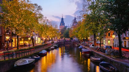 A medida que el crepúsculo desciende sobre Ámsterdam, los canales reflejan los tonos dorados de las hojas de otoño y las cálidas luces de la calle; países bajos está en el séptimo lugar de países con mejor calidad de vida