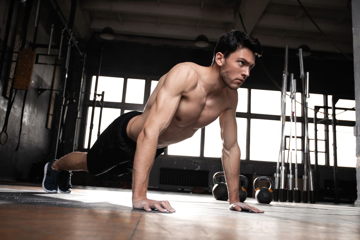 A muscular man doing a pushups at the crossfit gym.
