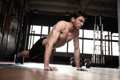 A muscular man doing a pushups at the crossfit gym.