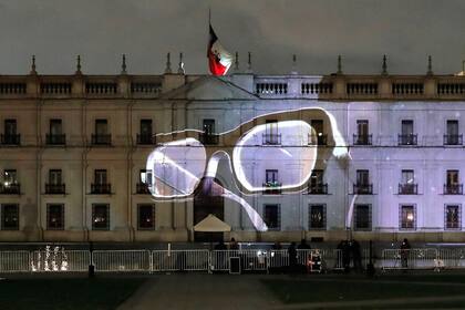 A pair of glasses representing the ones used by Chilean late President Salvador Allende, are displayed as commemorative images are projected on the facade of La Moneda Presidential Palace in Santiago on September 11, 2023, on the 50th anniversary of the coup d'etat that brought Augusto Pinochet to power. Chile on Monday marked 50 years of Pinochet's coup d'etat, with political divisions over the legacy of his brutal dictatorship on stark display. Commemorations of the violent US-backed ouster of Marxist leader Salvador Allende still evoke strong emotions, and police fired teargas and water cannon at protesters who vandalized the presidency on the anniversary's eve. (Photo by Javier TORRES / AFP)
