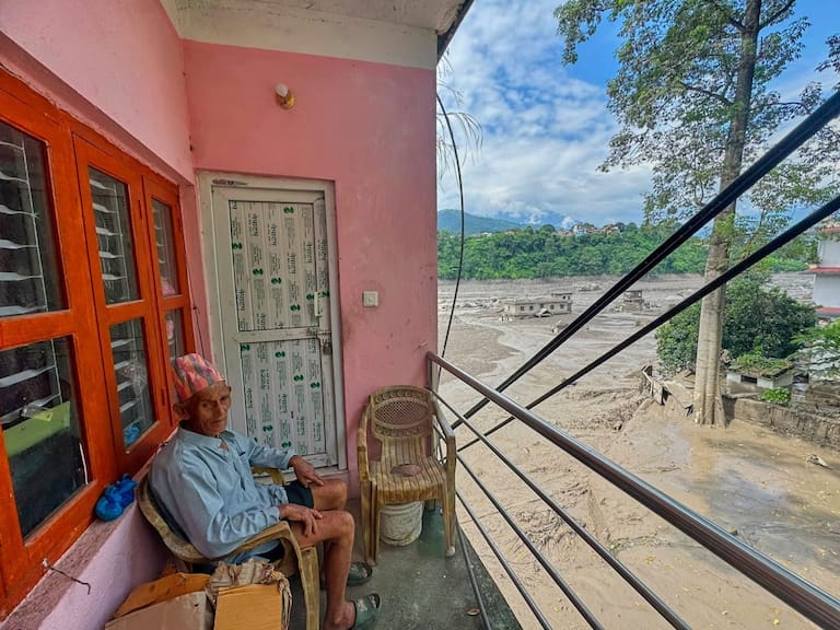 A resident sits on the balcony of his house surrounded by floodwaters and debris after flash floods caused the Trishuli River to swell in Nepal's Nuwakot district, Wednesday, Aug. 26, 2026. (AP Photo/Niranjan Shrestha)