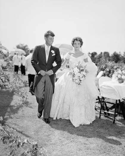 A scene from the Kennedy-Bouvier wedding. Groom John walks alongside his bride Jacqueline at an outdoor reception, 1953. Newport, Rhode Island. (Photo by Bachrach/Getty Images)