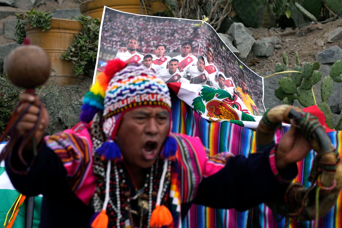 A shaman performs a good luck ritual in front of a photo of Peru's national soccer team, on San Cristobal hill in Lima, Peru, Friday, June 10, 2022. The shamans called on Mother Earth to support the Andean nation in its play-off game against Australia on Monday, to seal one of the final spots in this year's World Cup in Qatar. (AP Photo/Martin Mejia)