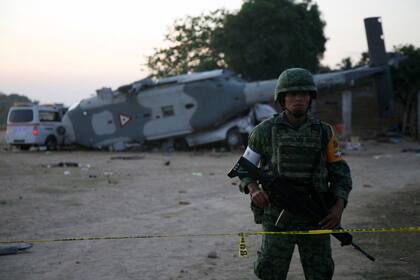 A soldier stands guard next to a military helicopter, carrying Mexico''s interior minister and the governor of the southern state of Oaxaca, crashed on top of two vans in an open field while trying to land in Santiago Jamiltepec, Mexico