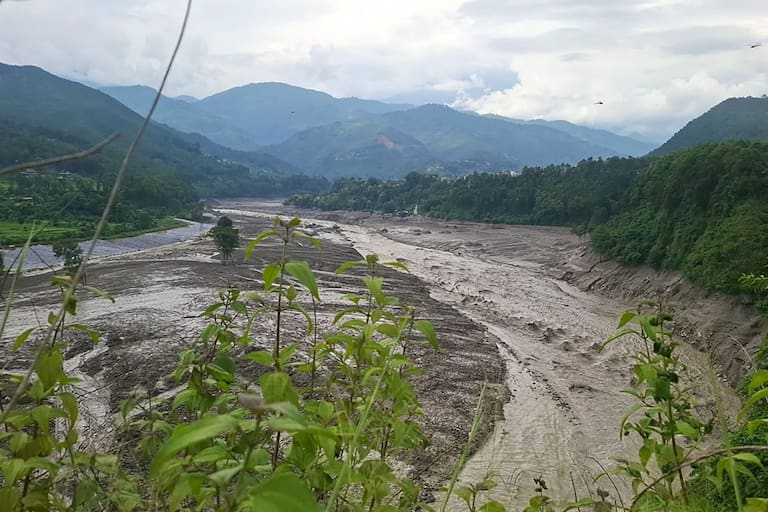 A torrent of muddy water surges through Trishuli river after flash floods in Nepal's Nuwakot district on August 26, 2026. Massive flooding killed eight people in Nepal on August 26, as Chinese state media reported "major casualties" from a mudslide at a Tibet trade hub on China's side of the nations' shared border. (Photo by Anup OJHA / AFP)