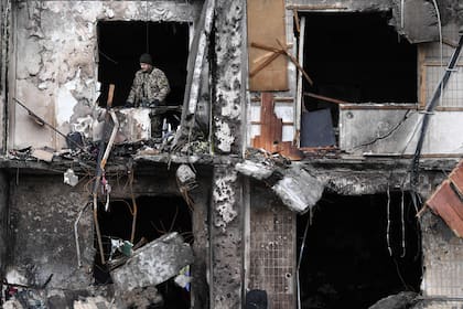 Un militar ucraniano en la ventana de un edificio residencial dañado en la calle Koshytsa, un suburbio de la capital ucraniana, Kiev, donde supuestamente cayó un proyectil