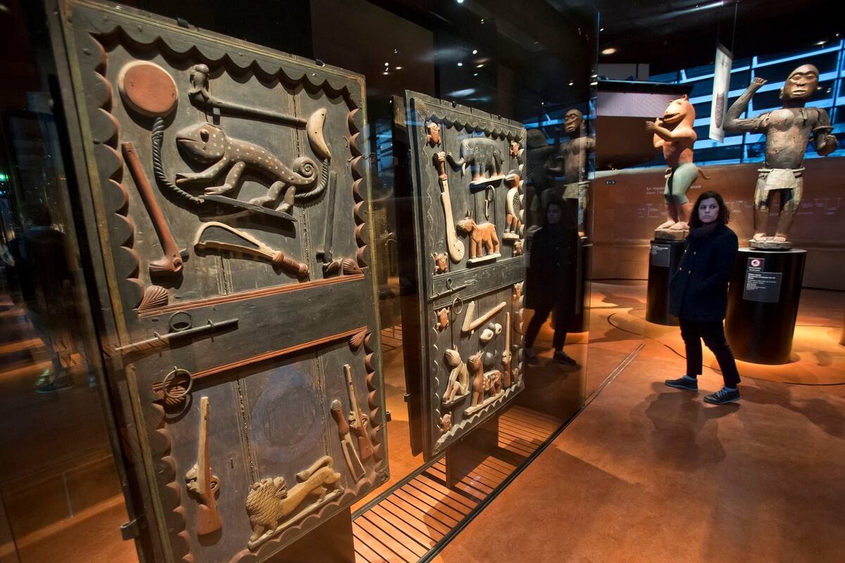 A visitor walks past a door of the kings palace Gele of the Dahomey kingdom, dated19th century, todays Benin, at Quai Branly museum in Paris, France, Friday, Nov. 23, 2018. From Senegal to Ethiopia, artists, governments and museums are eagerly awaiting a report commissioned by French President Emman