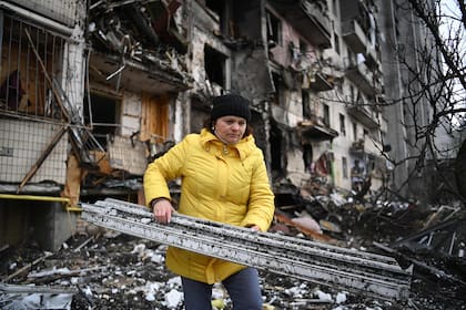 Una mujer limpia los escombros de un edificio residencial dañado en la calle Koshytsa, un suburbio de la capital ucraniana, Kiev