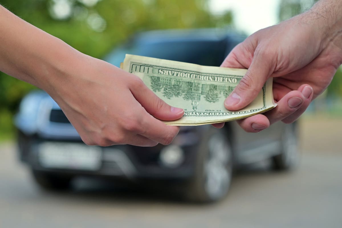 a woman gives cash to a man when buying a car. The car
